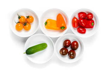 Set of white bowls full of fresh colorful vegetables top view close up
