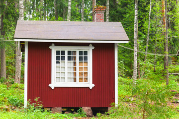 Fototapeta na wymiar Small Scandinavian red wooden house in forest