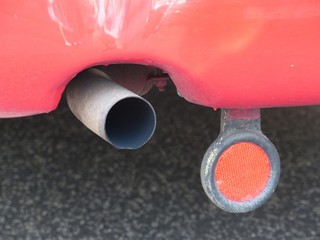 Auspuff und Katzenauge eines alten roten Bus aus Österreich im Sommer bei Sonnenschein beim...