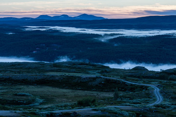 Fototapeta na wymiar Sunrise in the Swedish mountains, very early during summertime. Morning mist down in the valley.