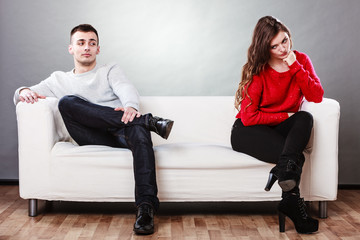 Young couple after quarrel sitting on sofa