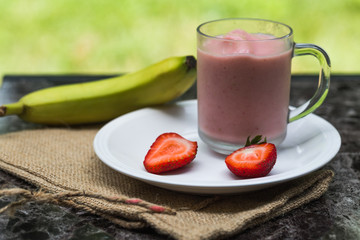 Strawberry banana smoothie with the whole banana and strawberry slices.