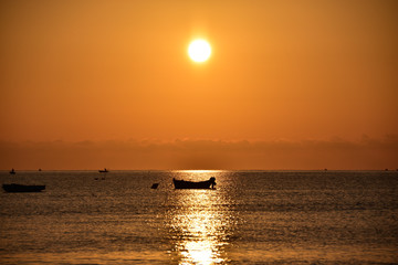 Alba con sole rosso e silhouette di barca