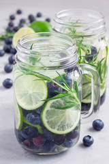Healthy infused water with fresh blueberry, lime and rosemary, vertical