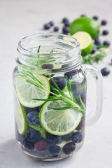 Healthy infused water with fresh blueberry, lime and rosemary, vertical