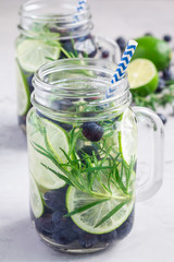 Healthy infused water with fresh blueberry, lime and rosemary, vertical