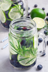 Healthy infused water with fresh blueberry, lime and rosemary, vertical