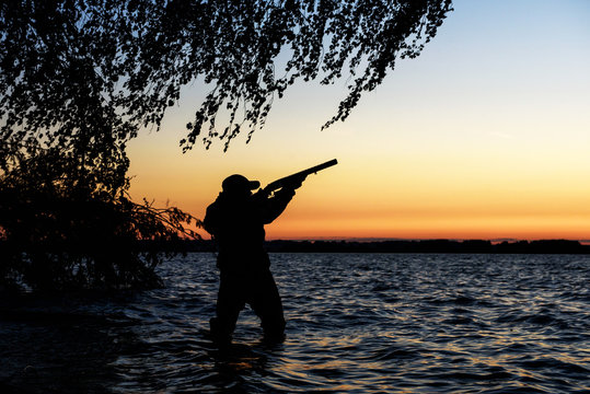 Hunter silhouette at sunset, while hunting on the lake
