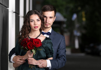 Elegant couple with bouquet of roses, outdoor