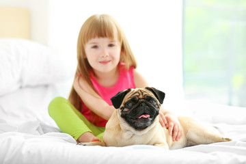 Beautiful girl and cute pug on bed
