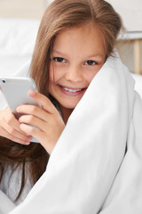 Cute girl with smartphone in blanket