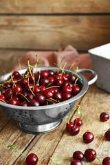 Cherries in colander on wooden table