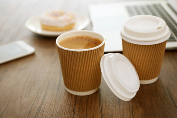 Paper cups of coffee on wooden table closeup