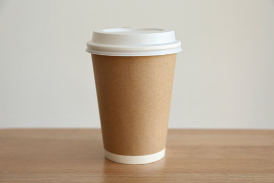Paper cup of coffee on light background