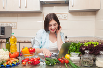 beautiful girl writes a salad recipe from the laptop and smiling