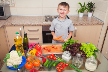 A boy plays with a carrot while cooking the salad