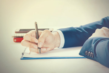 Closeup of Businessman writing on paper on notepad