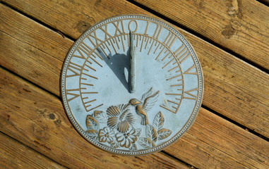 Fototapeta na wymiar Horizontal sundial on a wooden background showing nine o'clock
