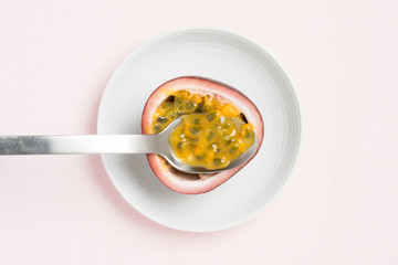 Passion fruit on spoon, pink background