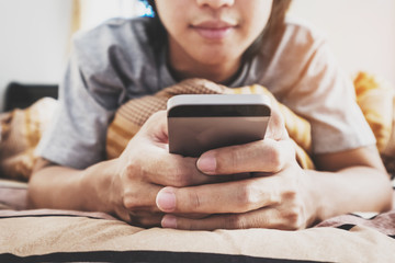 Asian guy using smartphone on bed in the morning, vintag etone