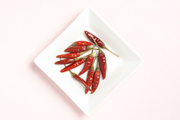 Red peppers on a white dish, pink background