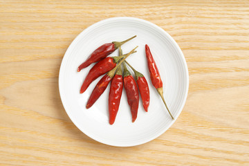 Red peppers on a white dish, wood background