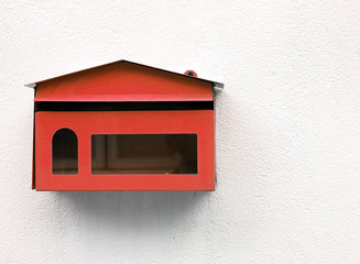 vintage red steel mailbox with transparent glass on white concrete wall