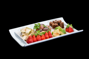 fruit salad in a plate with cookies on a black background