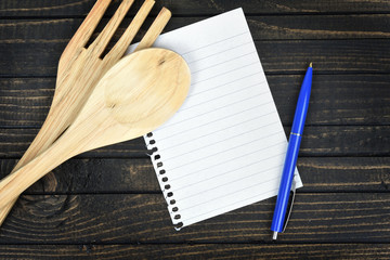 Kitchen utensils and empty page  on table