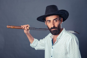 Man in casual dress code with hat and sword on gray background