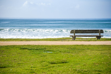 Naklejka na ściany i meble Wood bench near beach and sea