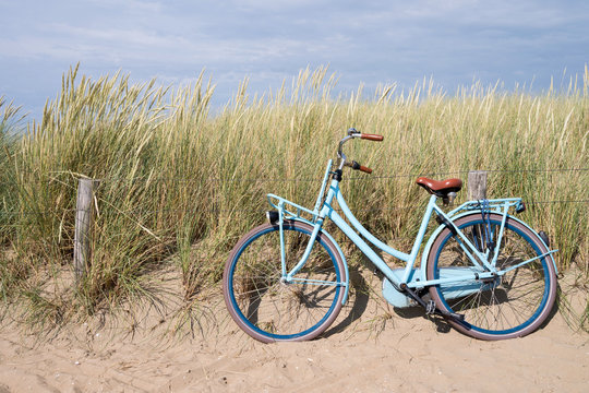 Fototapeta blaues Fahrrad abgestellt in den niederländischen Dünen