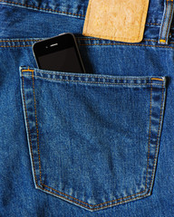 Smart phone in back pocket of blue denim jeans.