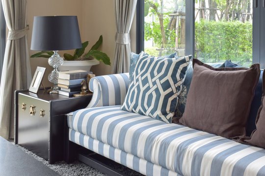 blue pattern pillows on striped sofa with black lamp in living room