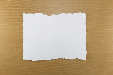 white paper tear on brown wood background.