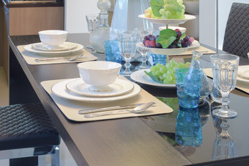 Chinaware setting on dining table with light blue crystal glass and fruits