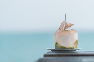 Coconut juice on wood table in blurred beach background