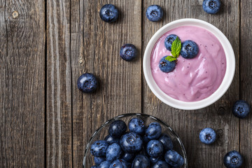 Homemade yogurt with fresh blueberry on a wooden background.