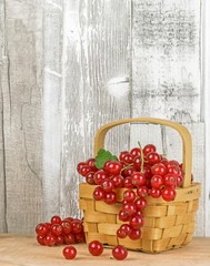 Red currants in a basket with a wooden background