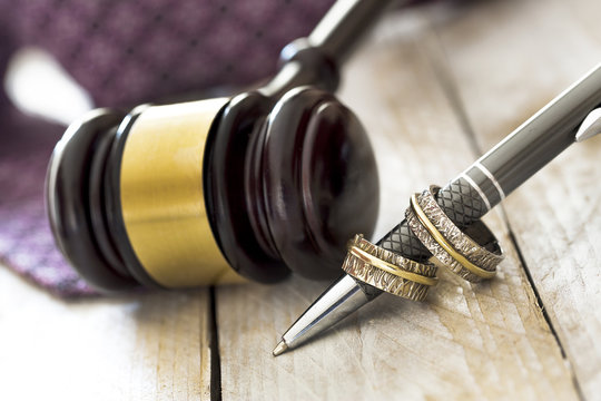 Divorce concept. Judge gavel, wedding rings and tie on wooden table