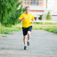 Running man jogging in city street park at beautiful summer day. Sport fitness model caucasian ethnicity training outdoor.