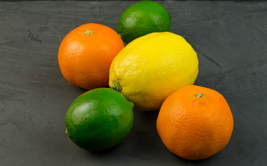 The fruit of lemon, mandarin and lime on a dark background.