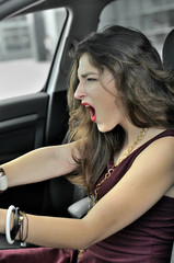 Fototapeta na wymiar Girl shouts while sitting behind the wheel of a car