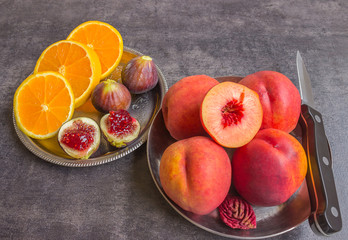 Colorful fresh fruits - figs, oranges and peaches on a dark back