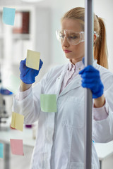 female chemist writing on sticky notes.