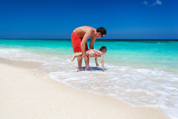 Father and daughter having fun on tropical beach