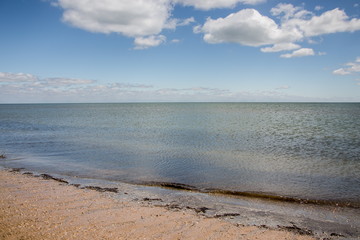 Calm sea, white clouds, yellow sand