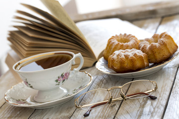 Coffee with cupcakes and book on the wooden table 