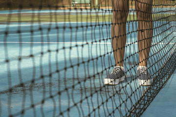 Legs of female tennis player.Close up back net 