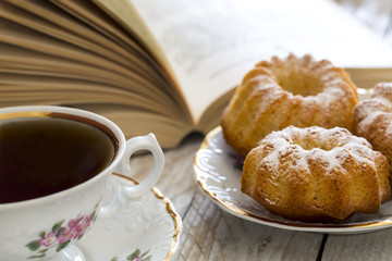 Coffee with cupcakes and book on the wooden table 